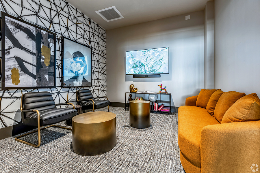Aer community lounge with plush seating, abstract artwork, and wall mounted TV.