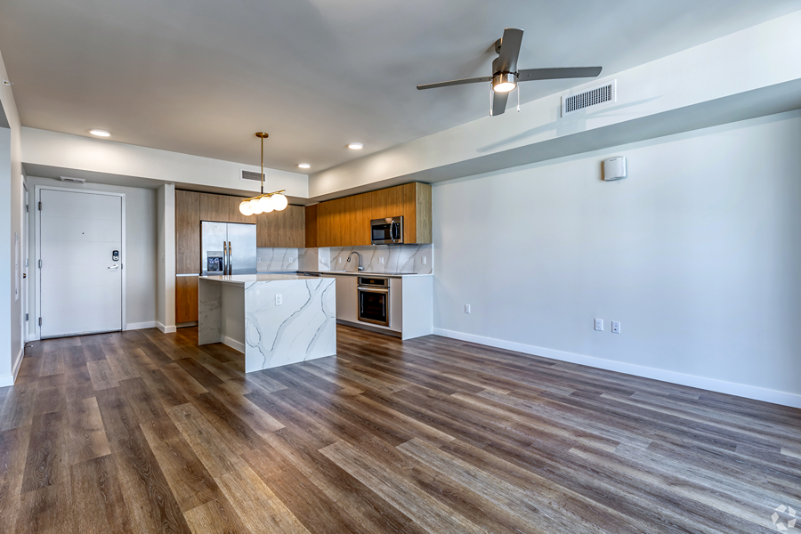 Aer apartment living area with modern kitchen and wood style floors.
