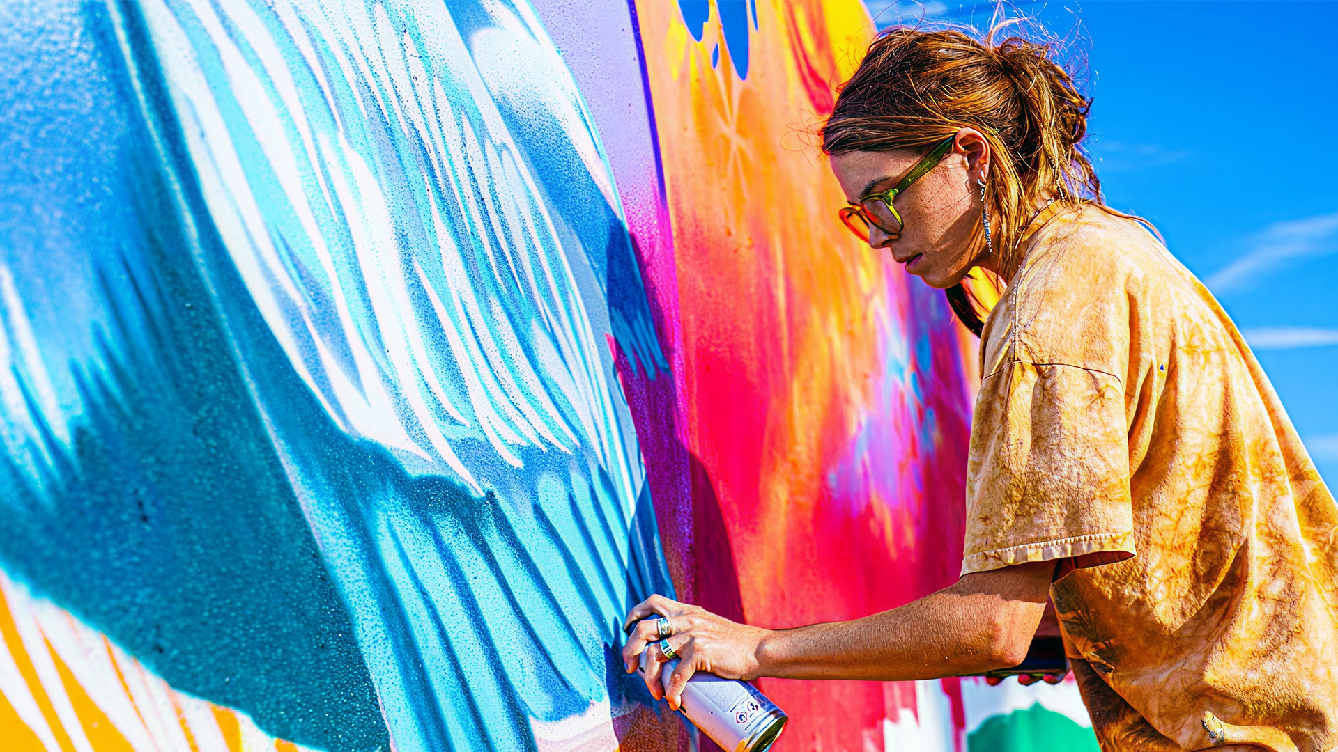 Aer Tampa artist-in-residence painting mural on sunlit wall.