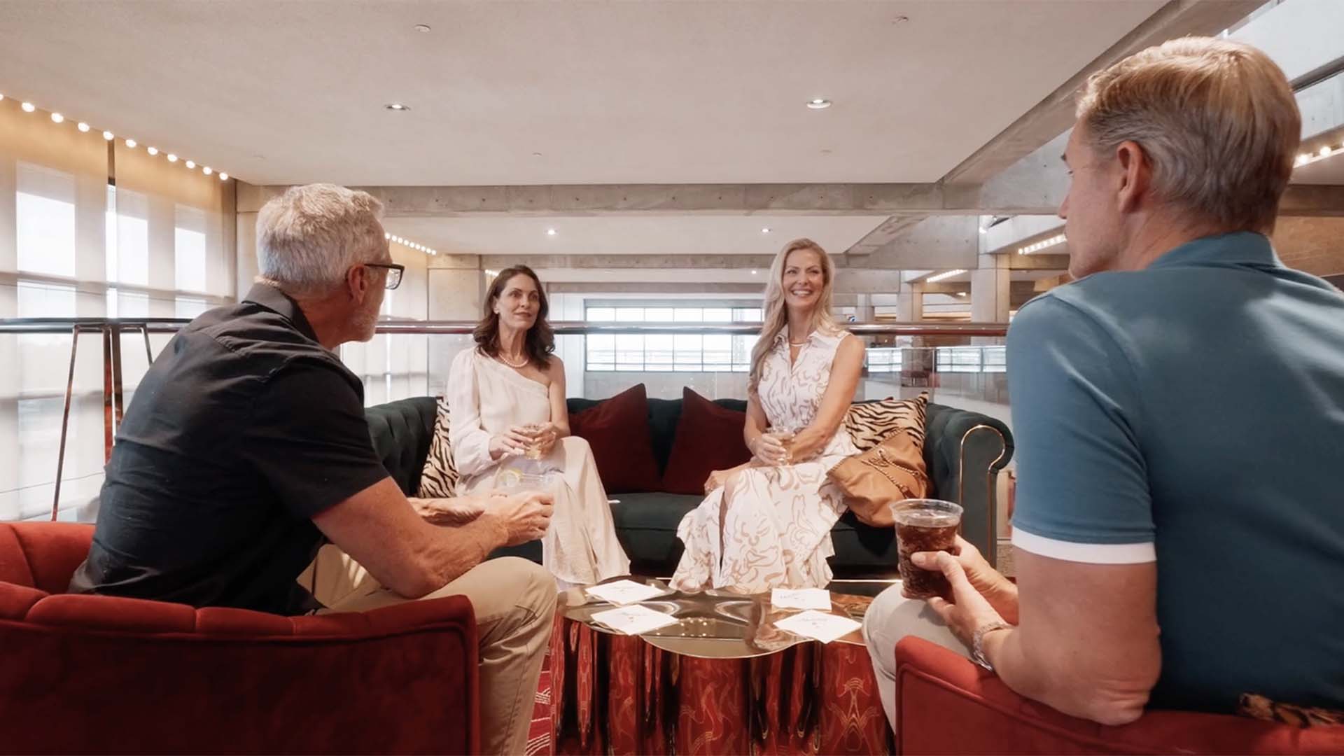 Two couples seated together at Straz Center enjoying cocktails on the mezzanine.